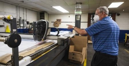 Industrial Polymers and Chemicals Chief Technical Officer Tom Kennedy with the company’s CNC Cutter tasked to outline and cut PPE gowns.